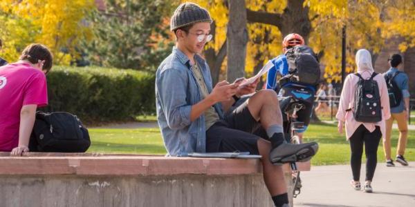 一个学生坐在外面的长凳上